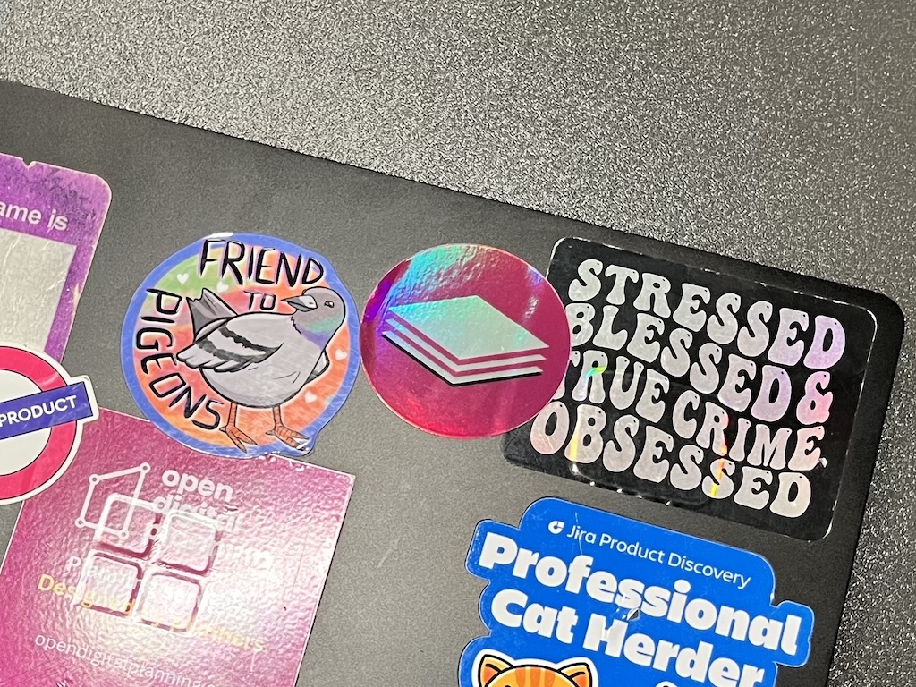 A laptop is covered in vibrant stickers – including the shiny Extract mission patch in pink.
